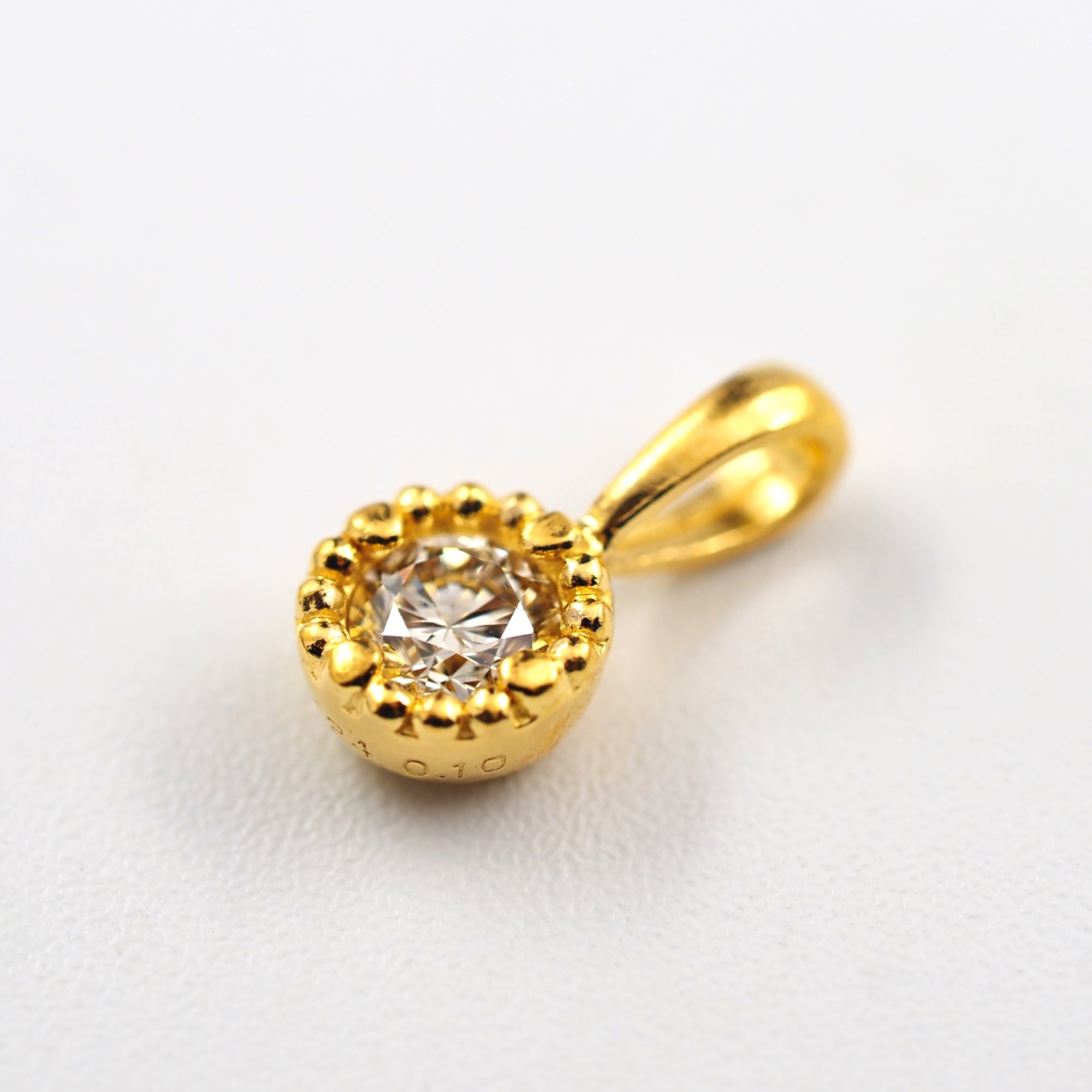 ミル打ちを施した枠でダイヤモンドを丁寧に包み込み、クラシカルな佇まいに仕上げたMITUREの純金ペンダント。