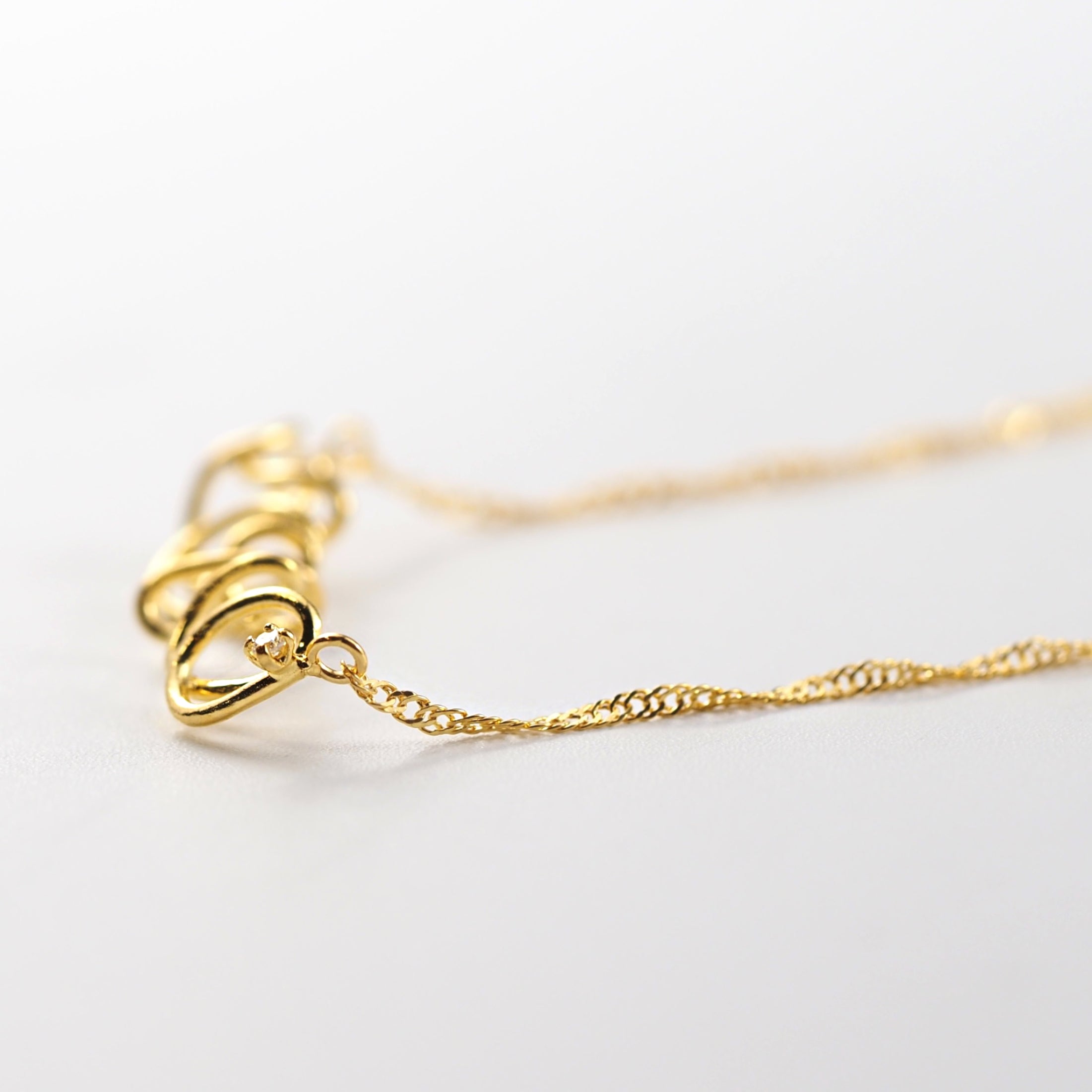 スクリューチェーンが光を受けて繊細にきらめく、華やかさを感じられるMITUREのK24ジュエリー。