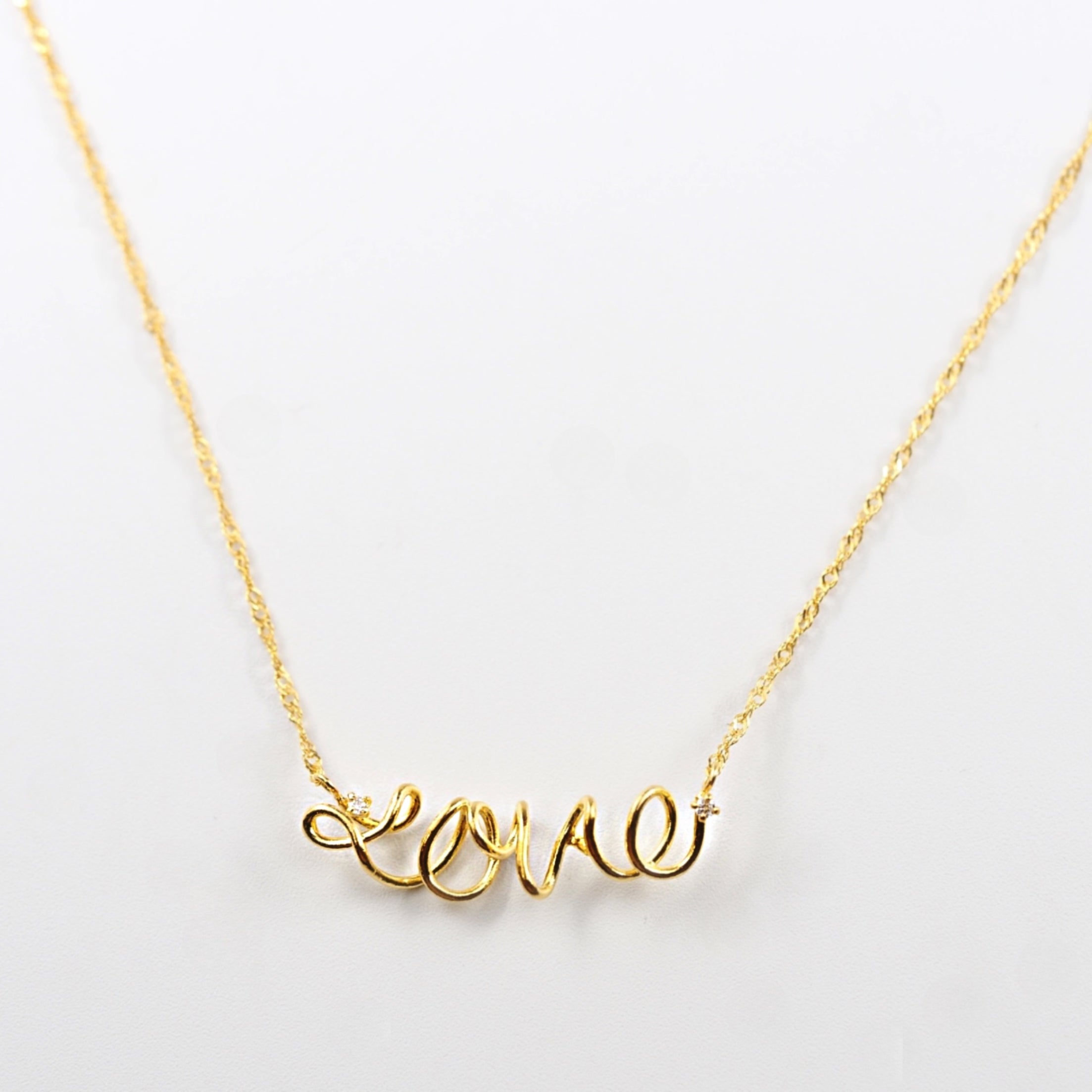 繊細なラインで描いたLoveモチーフを純金で仕立てた、MITURE（ミチュール）のK24ネックレス。流れるフォルムが上品に映えます。