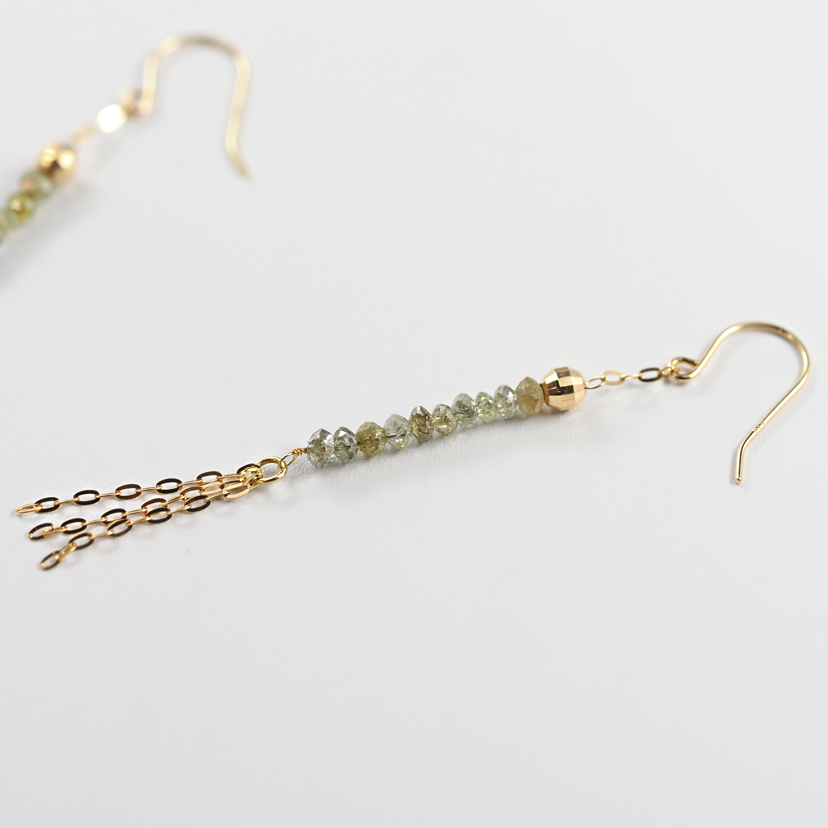 動くたびに軽やかに揺れ、繊細なラインとグリーンダイヤモンドの深みが引き立つMITUREのタッセルピアス。山梨県甲府市で製作。