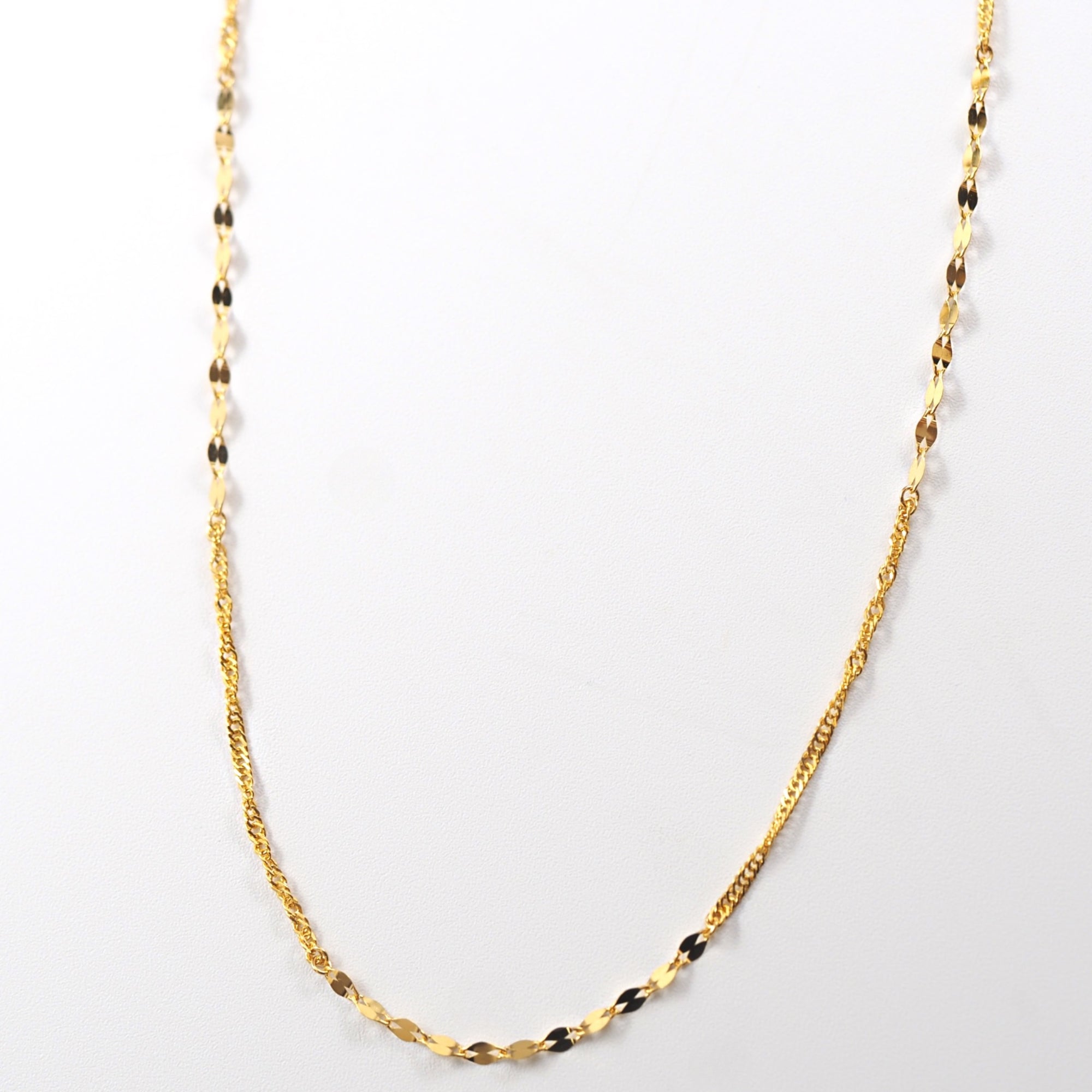 K24の深い輝きを生かした、MITURE（ミチュール）の42cm純金ネックレス。ペタルチェーンとスクリューチェーンの交差が上品に映えます。