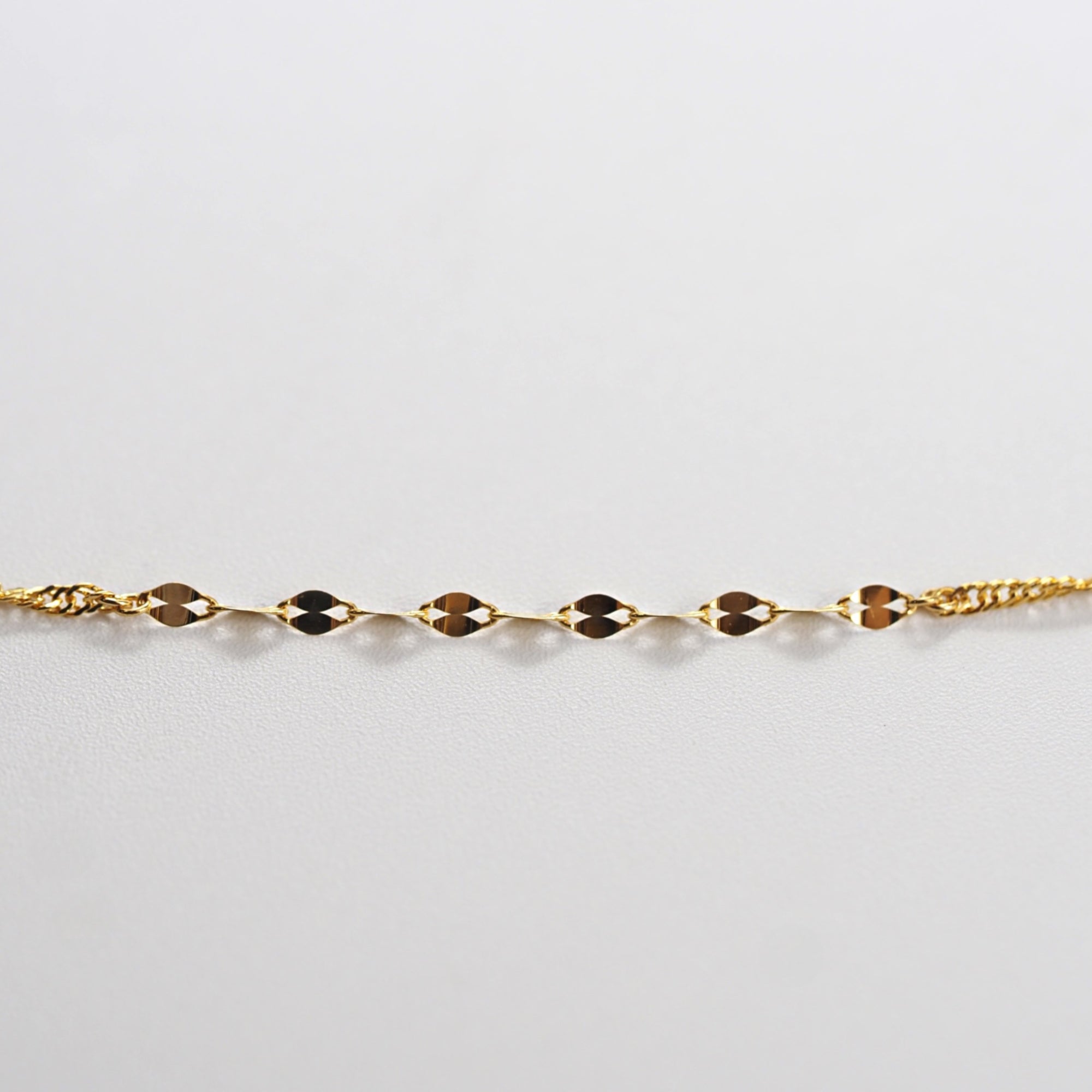 光を受けて細やかに揺れるチェーンが、角度によって豊かな表情を見せるMITUREの純金デザインネックレス。