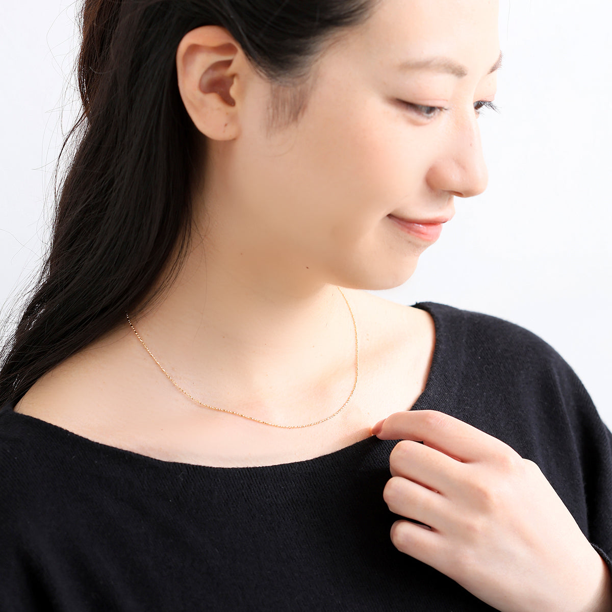 K18ゴールドのボールチェーンネックレスを着用したモデル。丸パーツと長丸パーツが繊細に輝き胸元を華やかに彩る、山梨県甲府市で製作したMITUREの18金ネックレス。