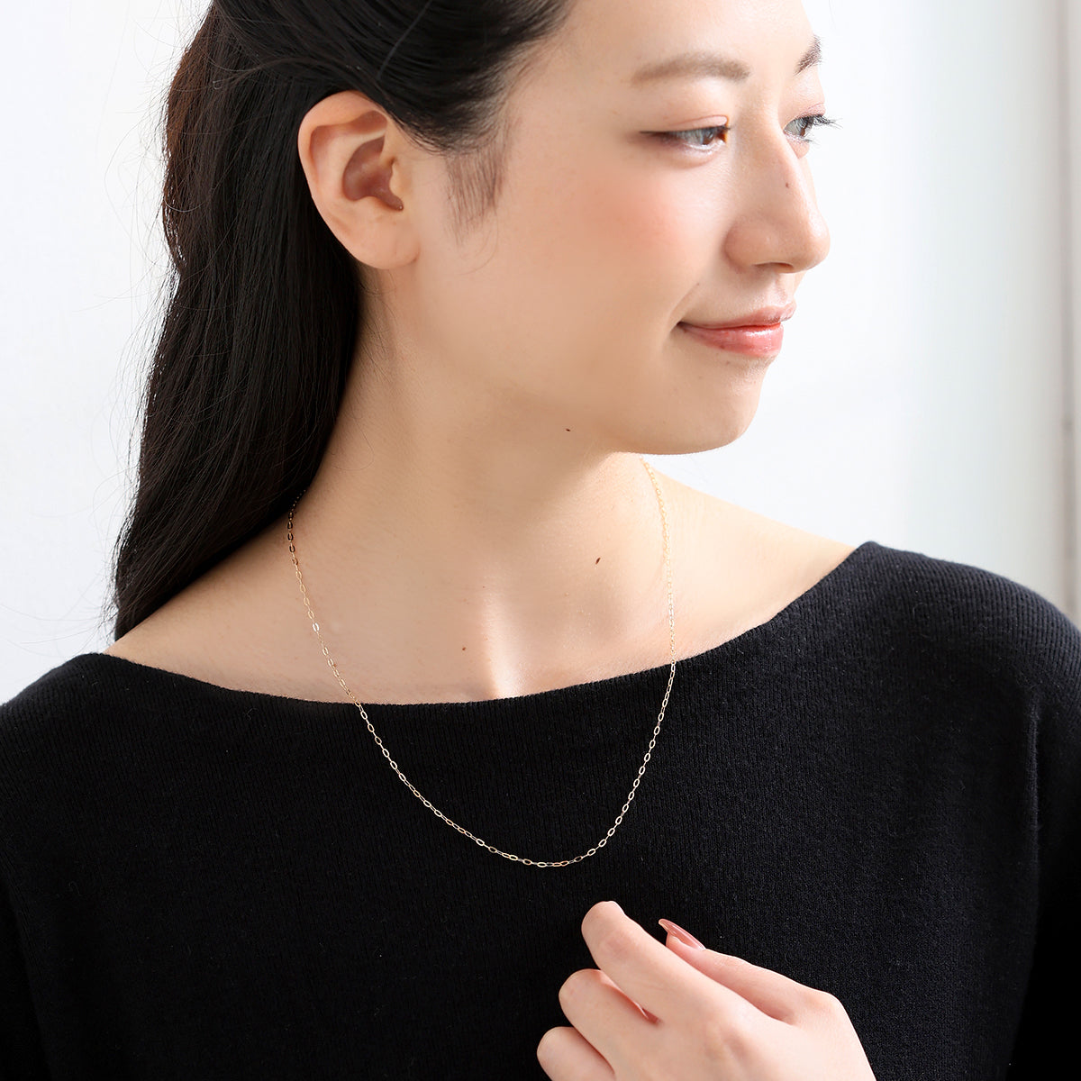 K18ゴールドのクリップチェーンネックレスを着用したモデル。幅感のあるチェーンが胸元で上品に輝く、山梨県甲府市で製作したMITUREの18金ネックレス。