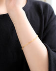 小さなネコモチーフが手元を愛らしく彩る、MITUREのK24純金ブレスレット着用イメージ。深みのある黄金色が、大人の装いに上品な華やかさと遊び心を添えます。